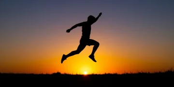 Athlete jumping at sunset, symbolizing peak physical condition and successful training.