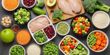 Colorful array of budget-friendly healthy ingredients and prepared meals on a rustic wooden table, showcasing affordability and nutrition.